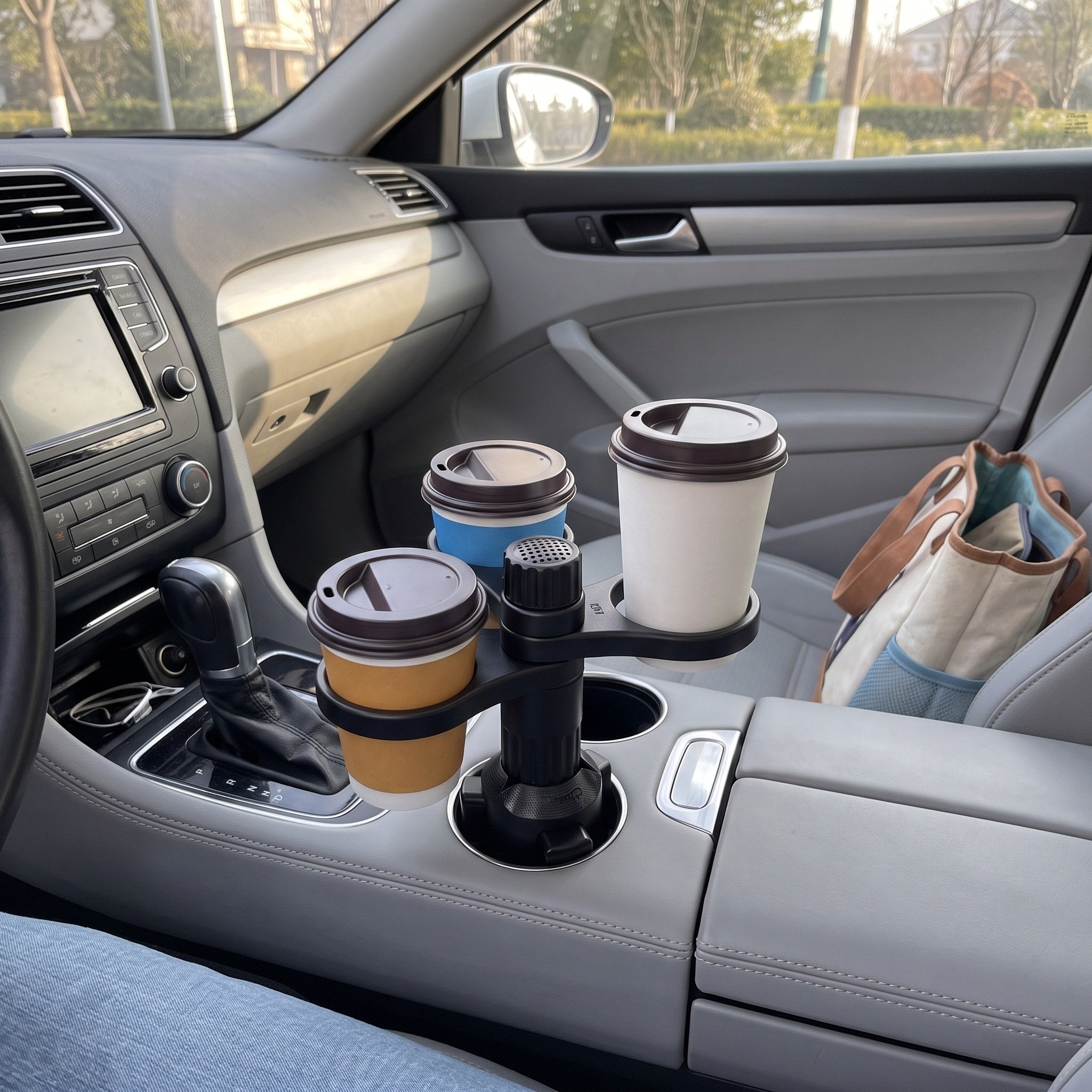 Three coffees in a parked silver sedan, seen from the owner’s seat