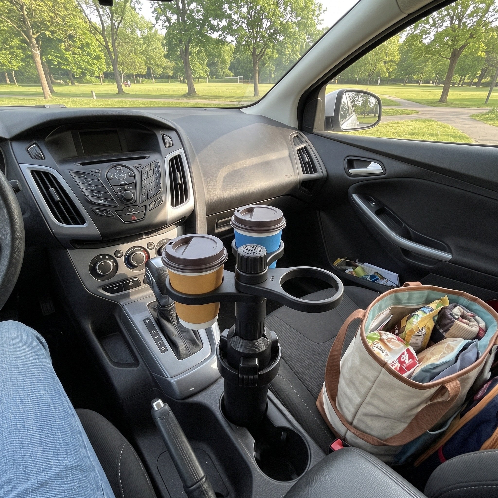 Two cups in a parked hatchback with a picnic bag on the floor