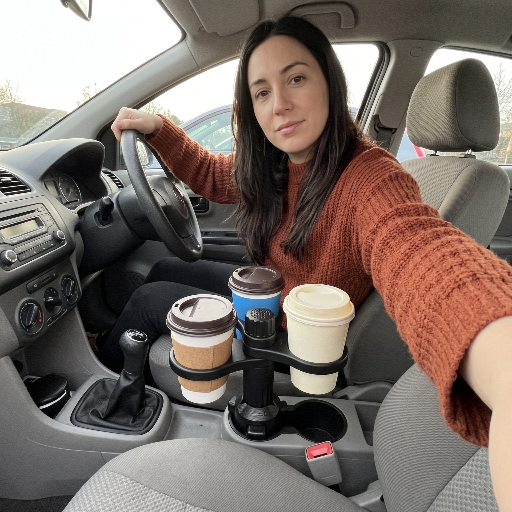 Priya’s parked-hatchback selfie with three cups in the console holder